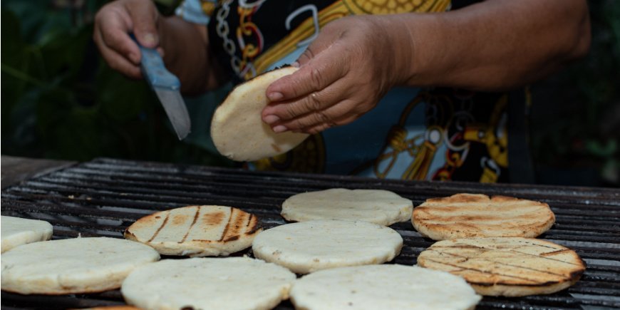 Eine Person bereitet eine Arepa auf dem Grill zu
