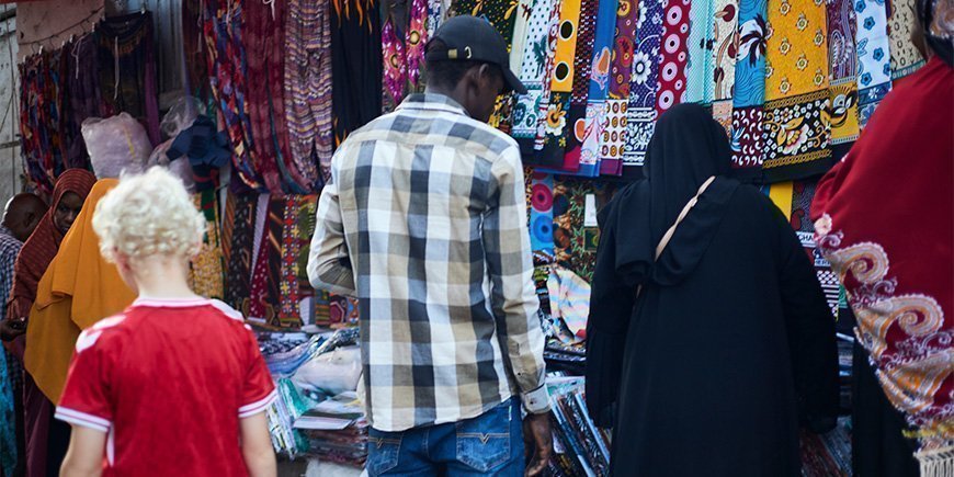 Junge geht zwischen den Einheimischen auf dem Markt in Stone Town spazieren